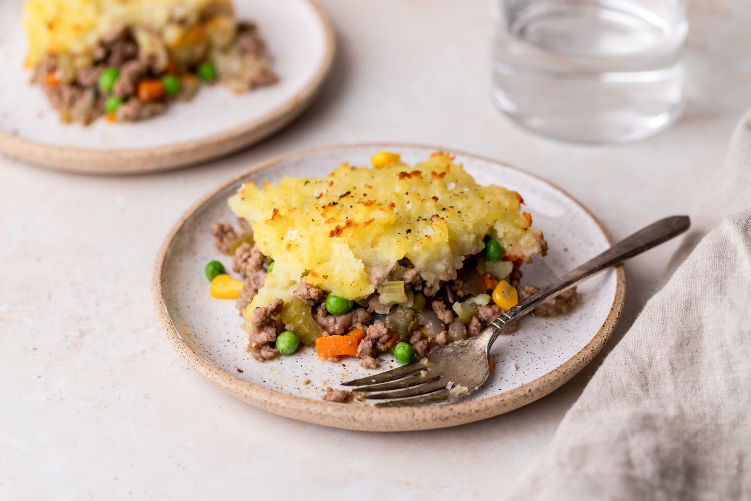 A slice of shepherd's pie on a plate with a fork.