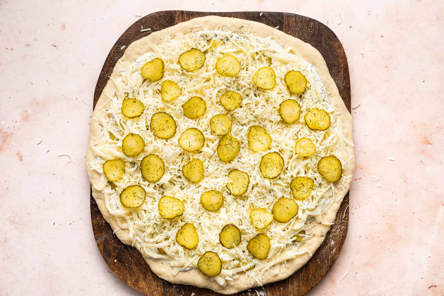 Pickles topping a pickle pizza ready to bake