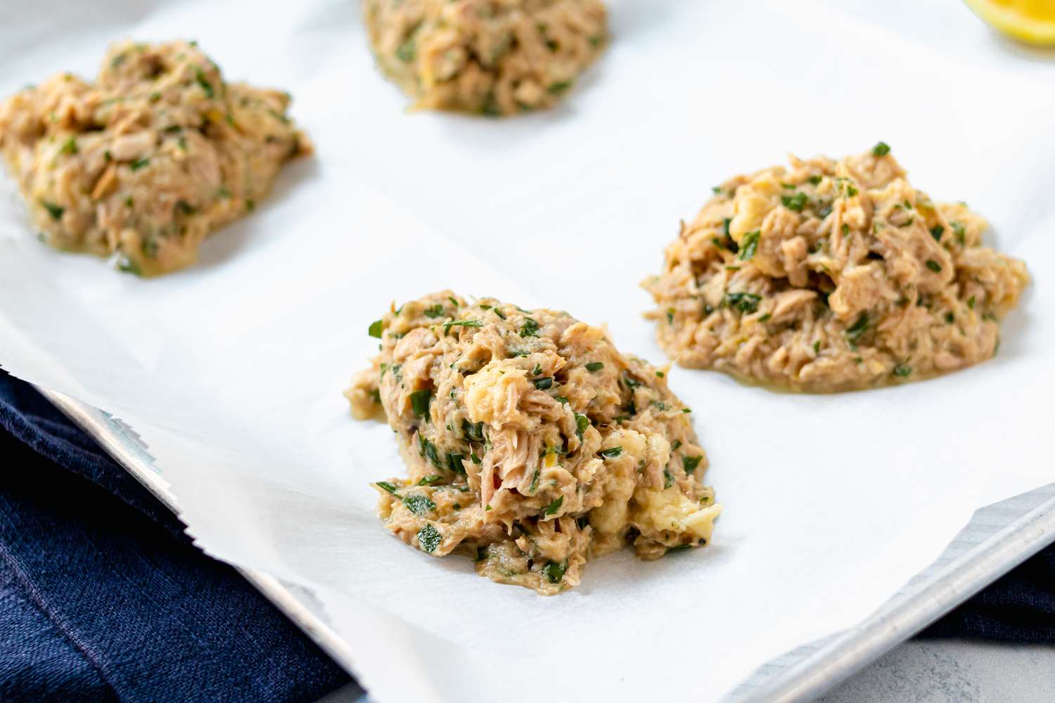 Tuna patties scooped on parchment paper to show how to make tuna fish.