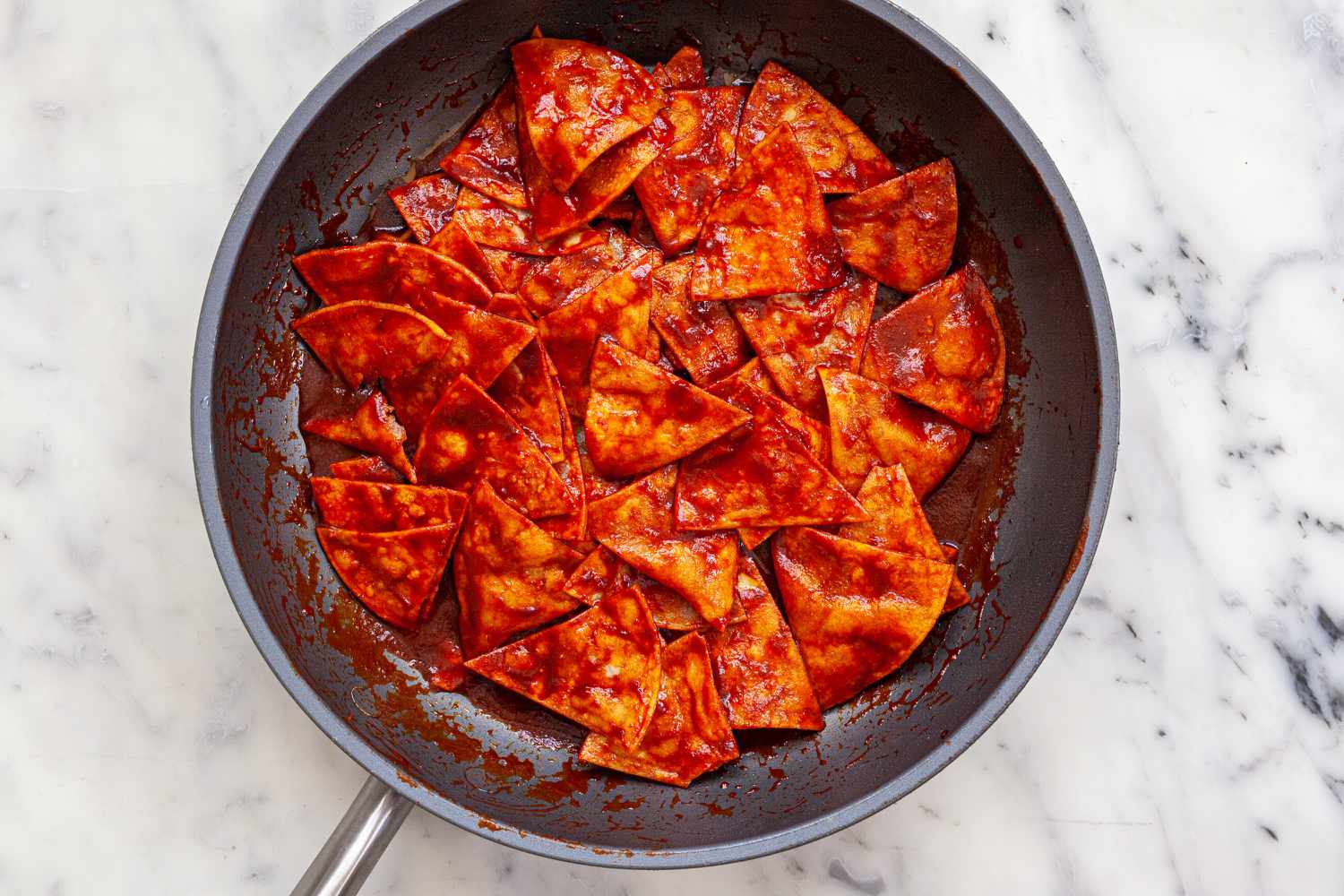 Chips and sauce in a skillet to show how to make chilaquiles.