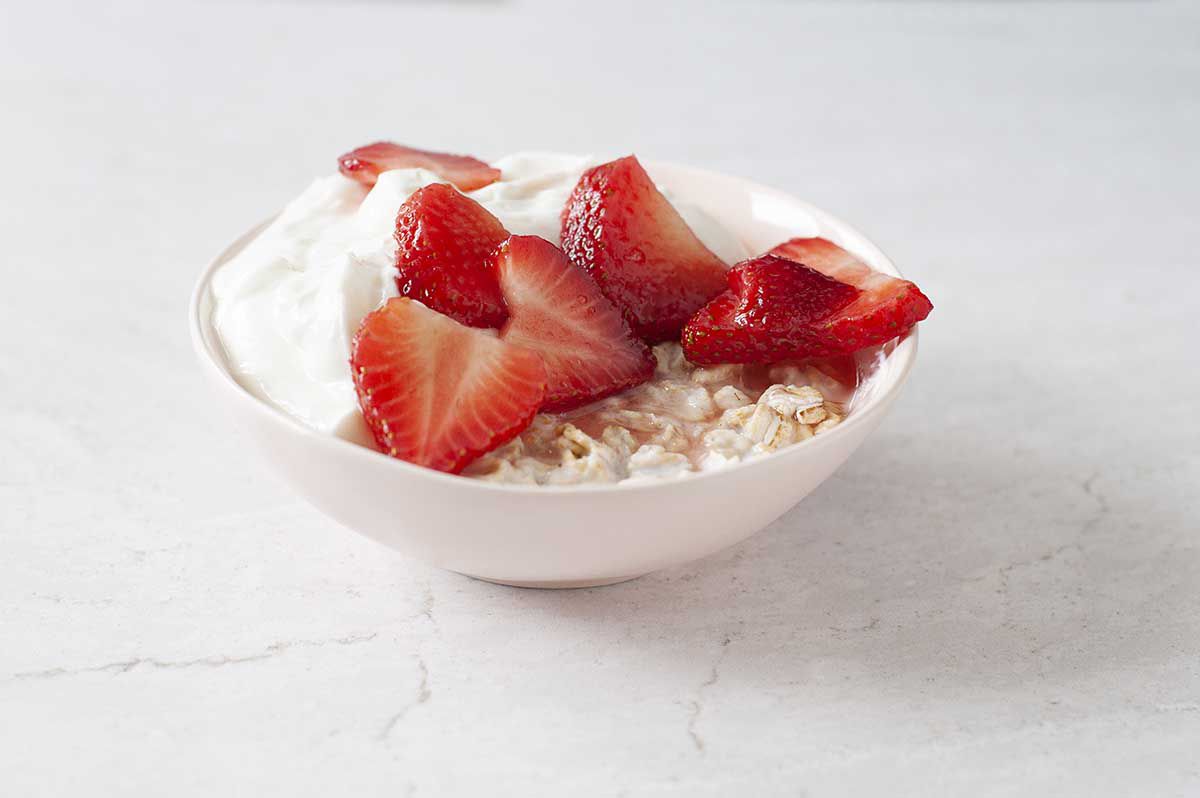Bowl of easy overnight oats topped with strawberries and yogurt.