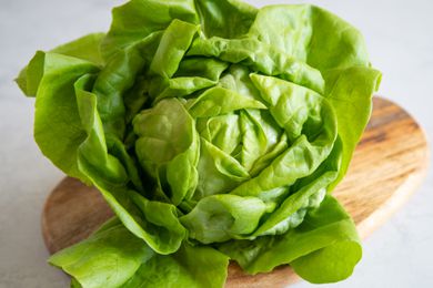 Head of green lettuce on a wood cutting board