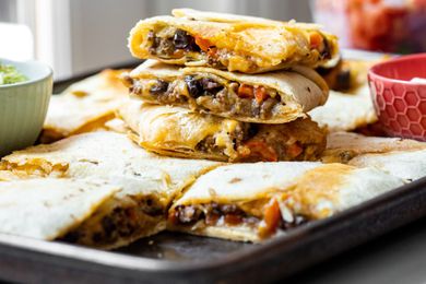 Stack of Loaded Sheet Pan Quesadillas Pieces on Sheet Pan with More Quesadilla Pieces 
