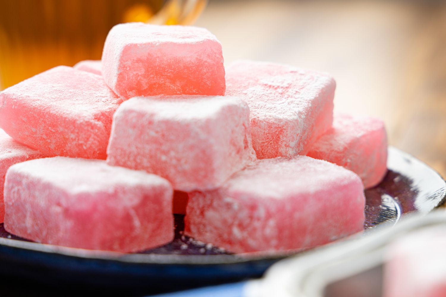 Turkish Delight on a Plate on a Wooden Counter, and in the Background a Cup of Tea