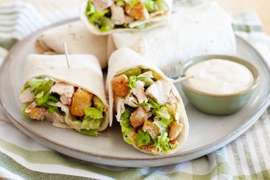 Chicken Caesar Wraps Cut in Half on a Plate with a Small Bowl of Dressing