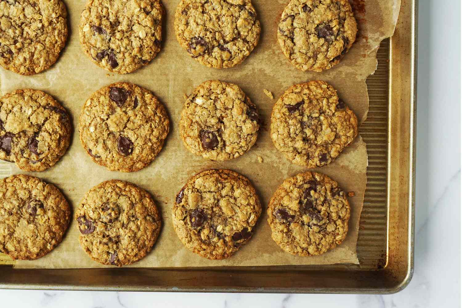 A tray of oatmeal chocolate chip cookies on parchment paper
