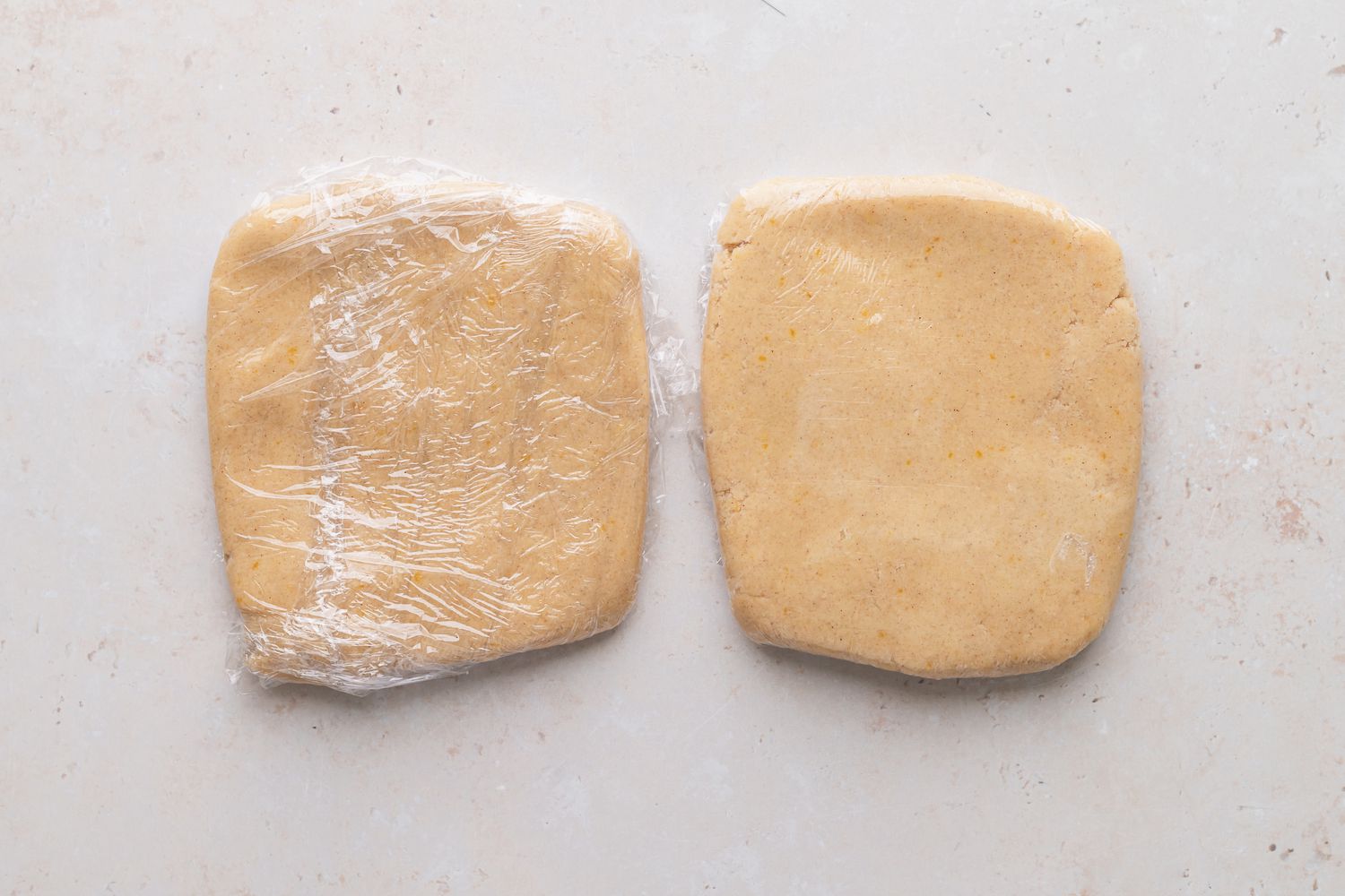 Dough to make classic linzer cookies in two flattened balls wrapped in plastic wrap.