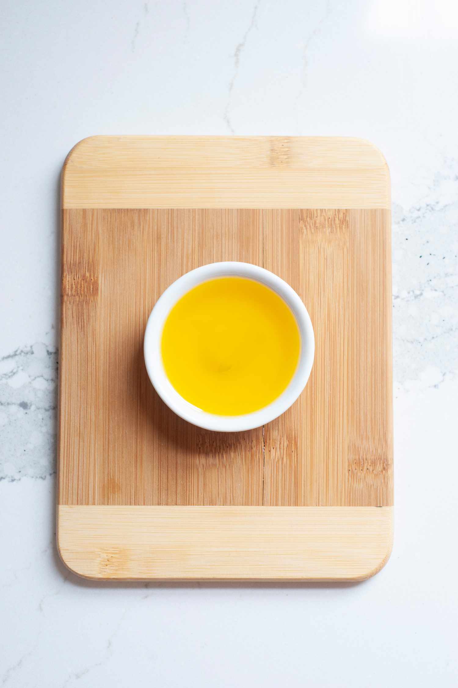 Flaxseed oil in a white bowl on a wood cutting board