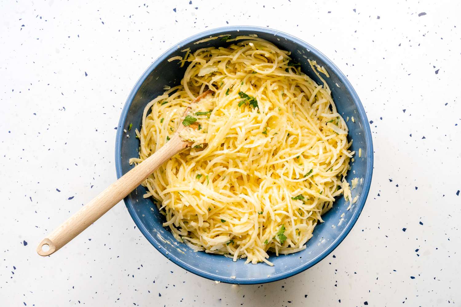 Potato Kugel Ingredients Mixed Together Using a Wooden Spoon