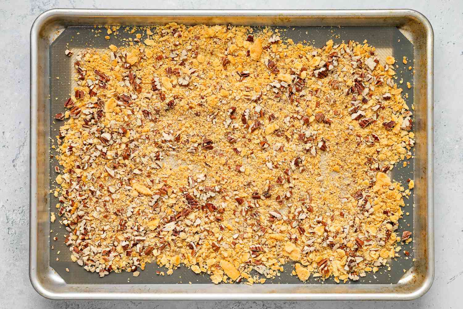 Toasted crushed crackers and pecan pieces on a baking sheet for ritz torte recipe