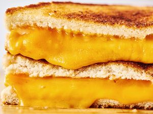 A closeup of a grilled cheese sandwich with melted cheese oozing between slices of toasted bread