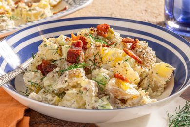 bowl of ranch potato salad, and in the background, a platter wtih more and a glass of water