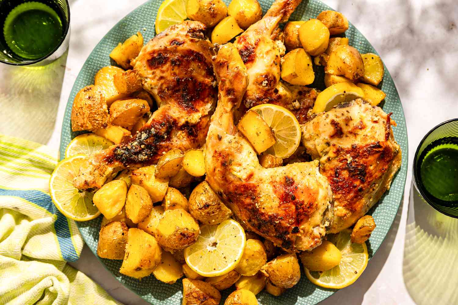 A large plate of Greek-style roast chicken with potaotes and lemon slices