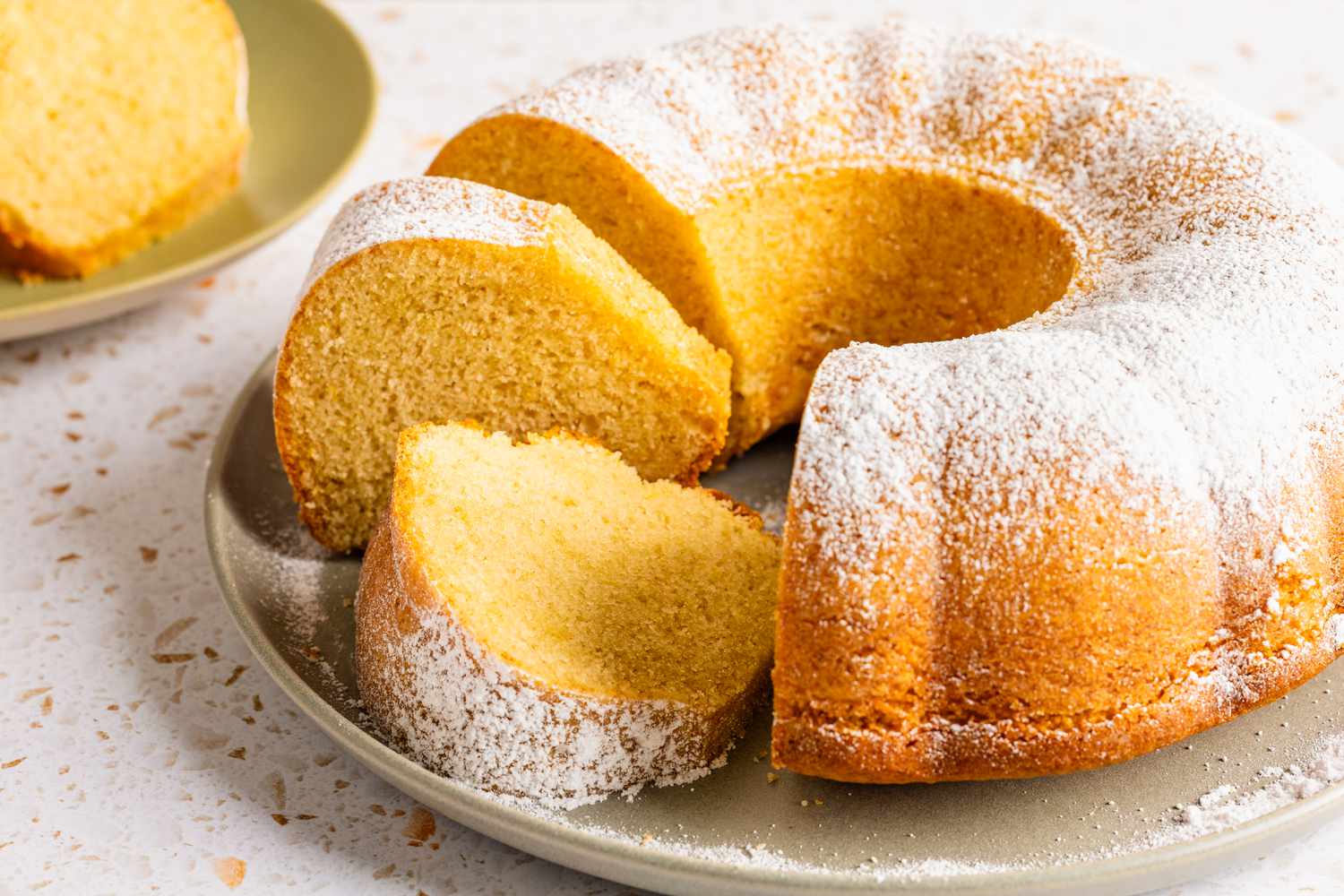 ciambellone on a platter with some of it cut into slices, and in the background, a slice on a plate 