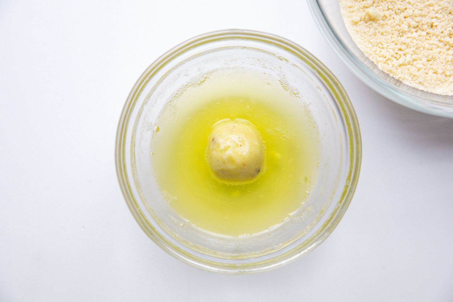 Dredging Step: Potato Croquette Ball Dipped in a Bowl of Egg Whites