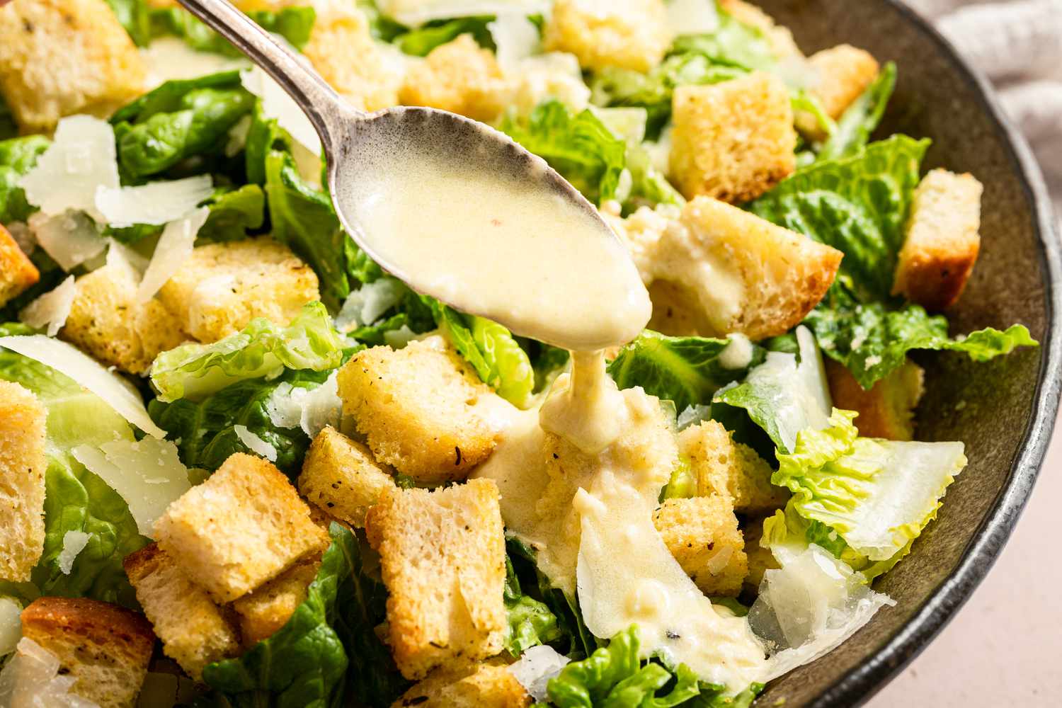 Caesar dressing spooned onto a caesar salad