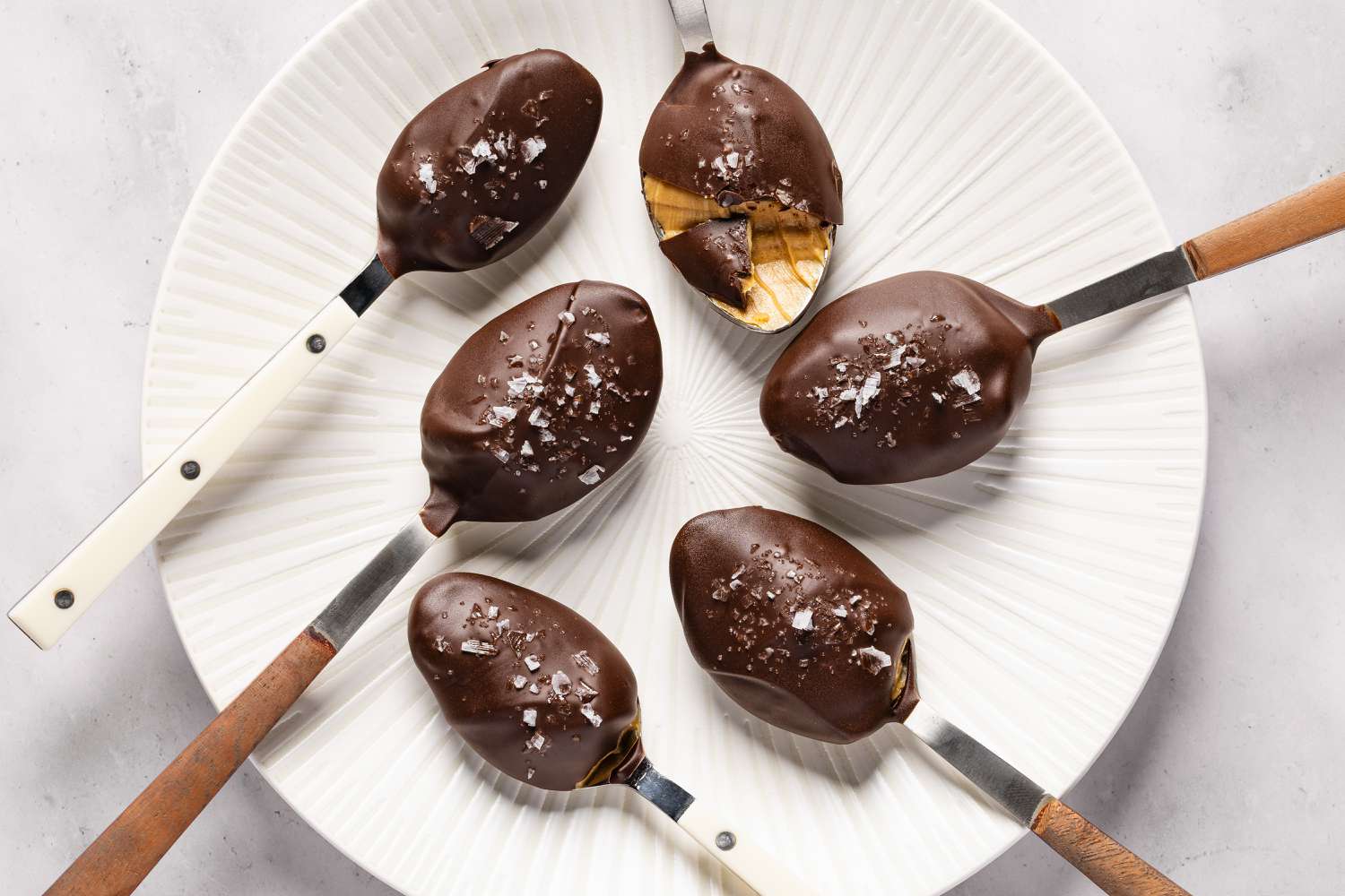 Overhead shot of six spoons with chocolate and sea salt covered peanut butter