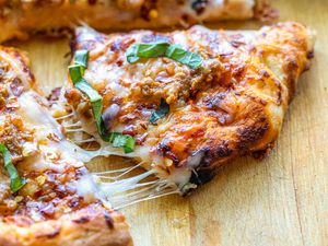 Easy pizza recipe with sausage cut into slices with melted cheese strung between the slices.