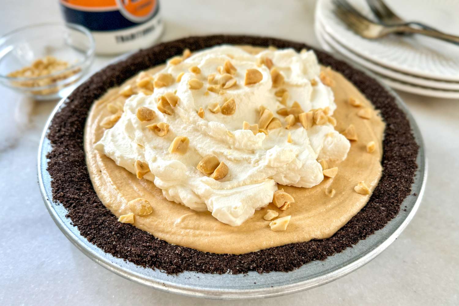A peanut butter pie with whipped topping and nut garnish on a table