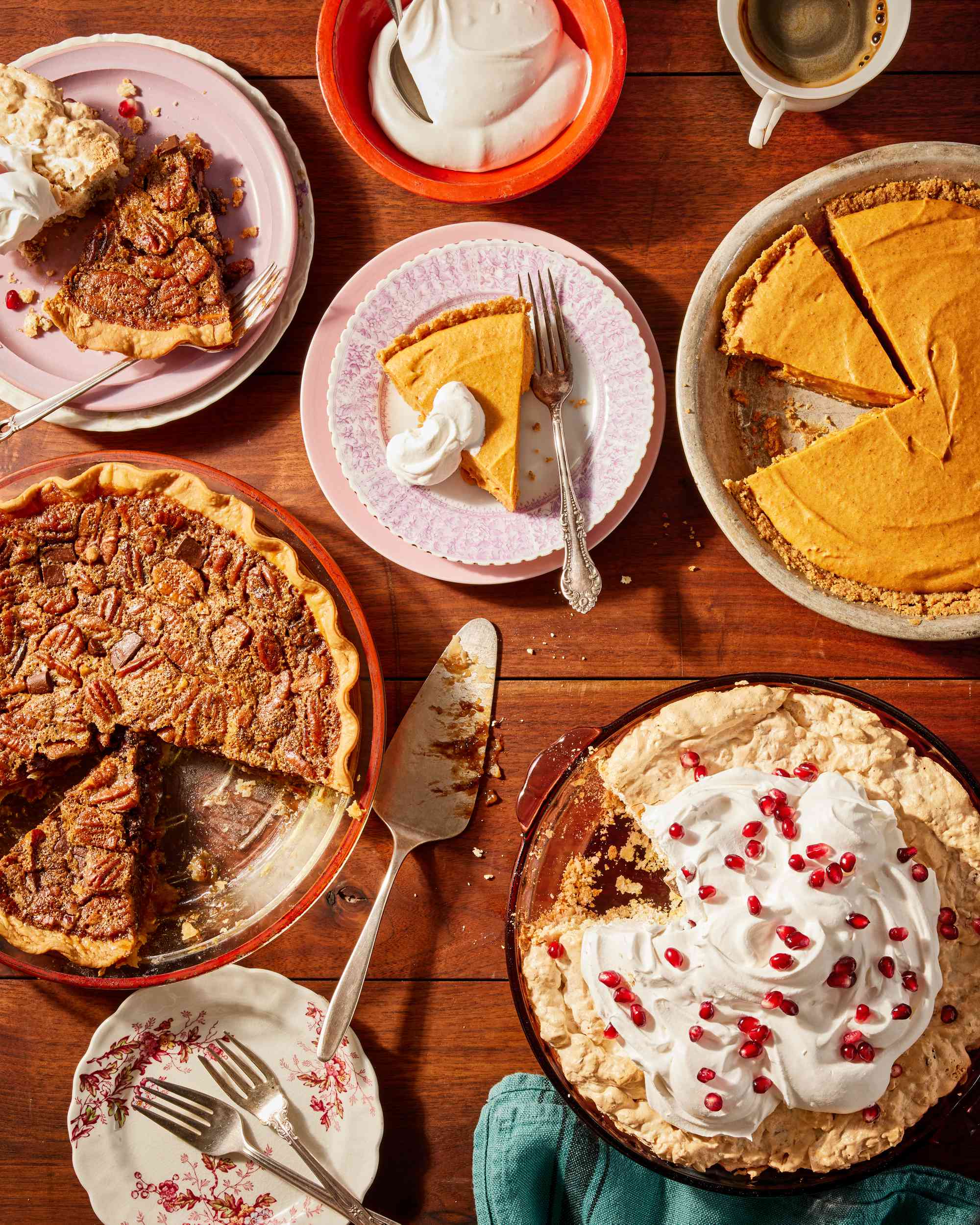 Table filled with Thanksgiving pies, including pumpkin, chocolate pecan, and soda cracker pie.