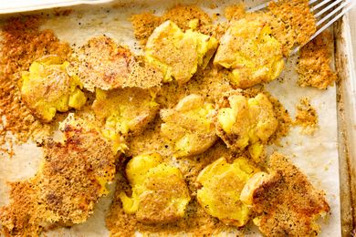 Crispy Parmesan Smashed Potatoes on a parchment lined sheet-pan