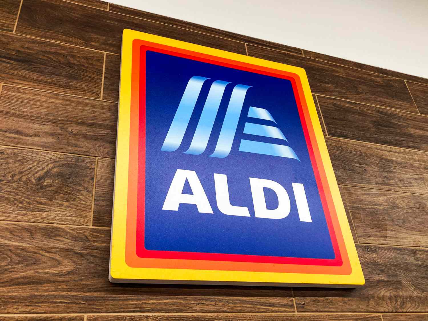 A sign with the ALDI logo mounted on a woodentextured wall