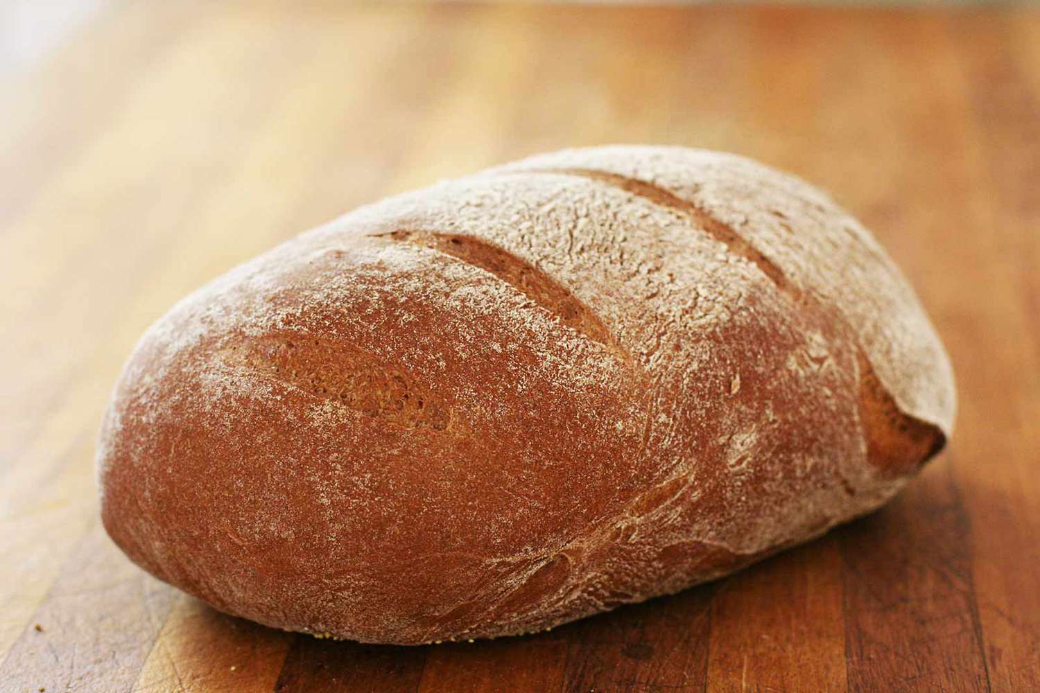 A freshly baked loaf of rye bread on a wood table