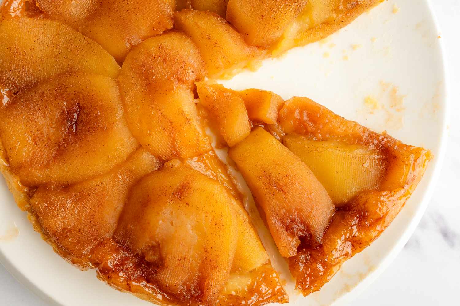 A tarte Tatin with visible caramelized apple slices on a plate one slice is visibly removed