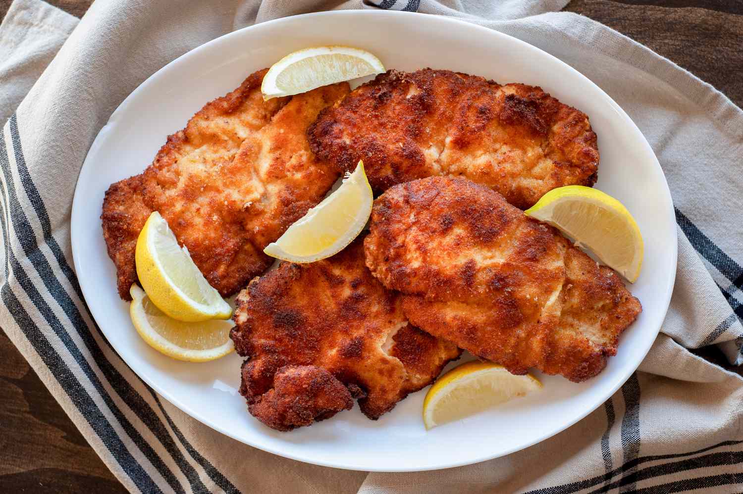 chicken schnitzel on platter with lemon wedges