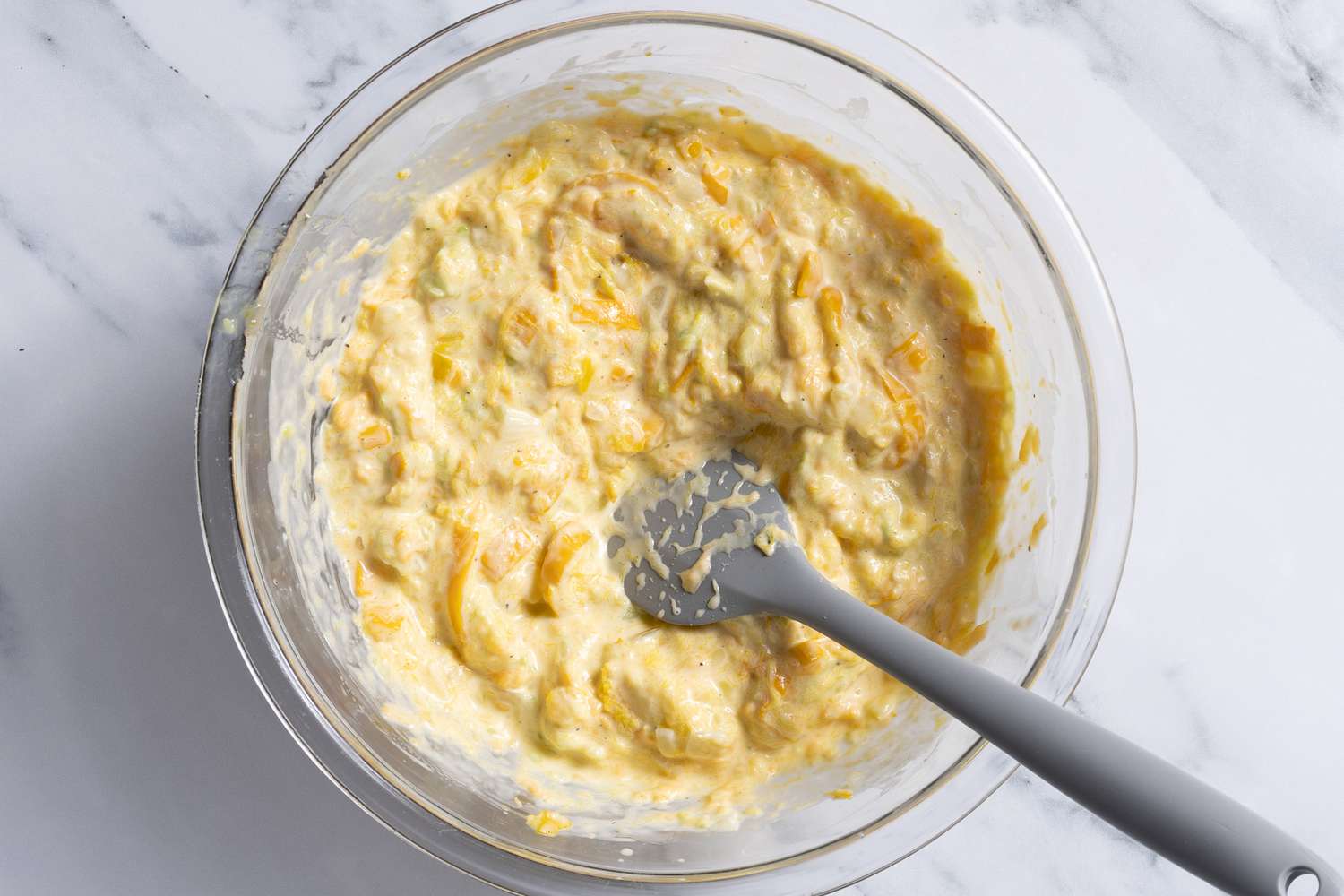 mashed squash mixed with a bowlful of other ingredients for summer squash casserole recipe