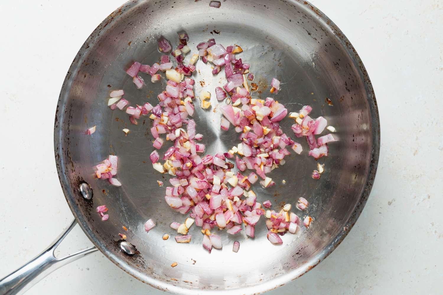 A skillet with sauteed onions and garlic to make a turkey burger recipe.