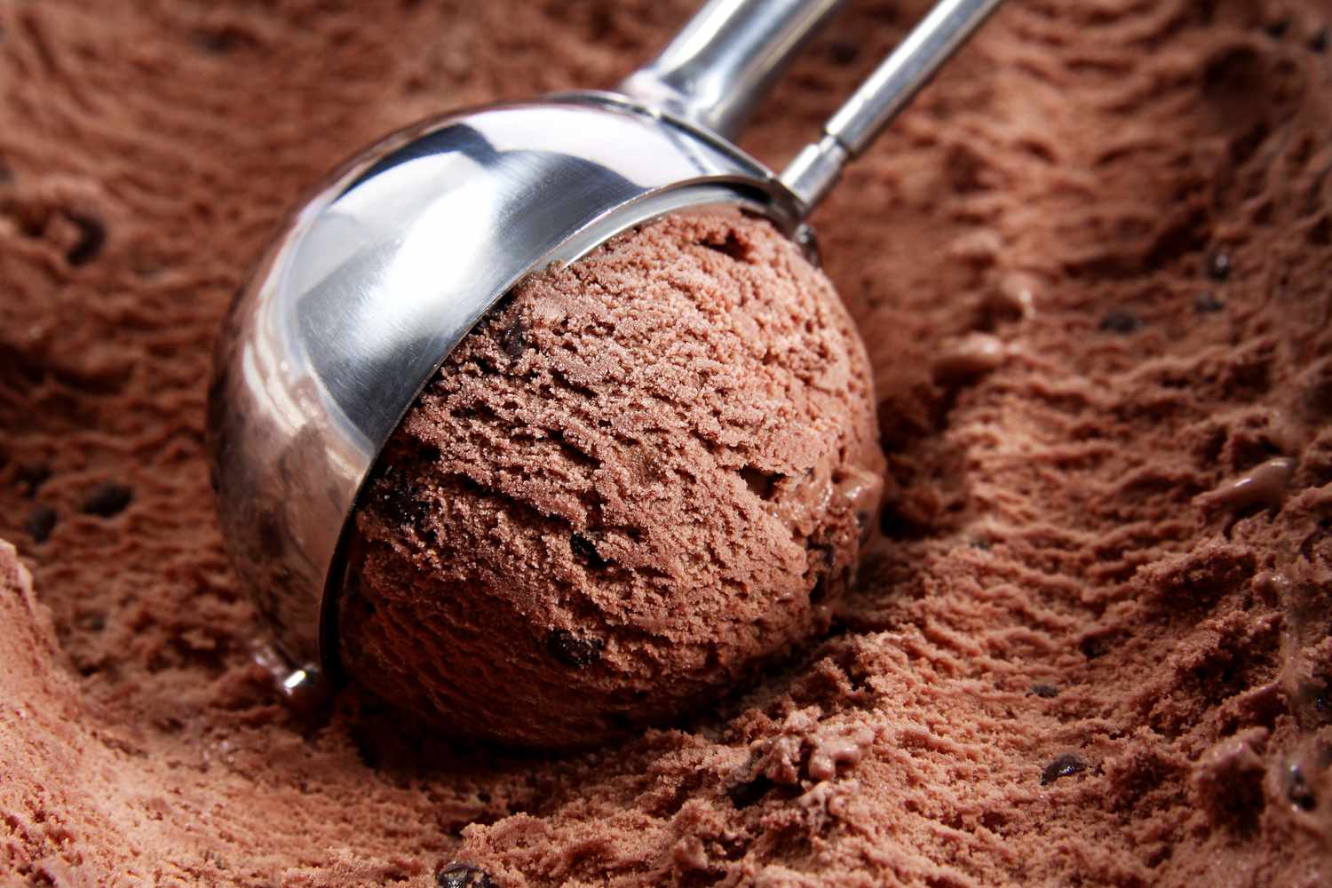 A scoop of chocolate ice cream in a metal scooper