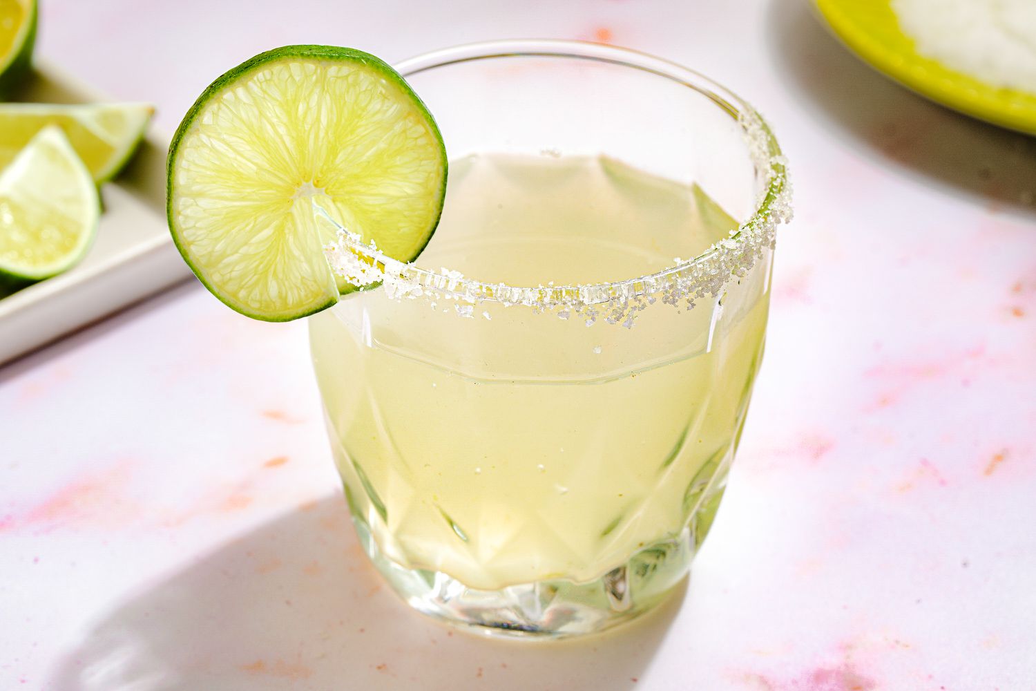 A margarita in a glass with a salted rim, garnished with a lime wheel