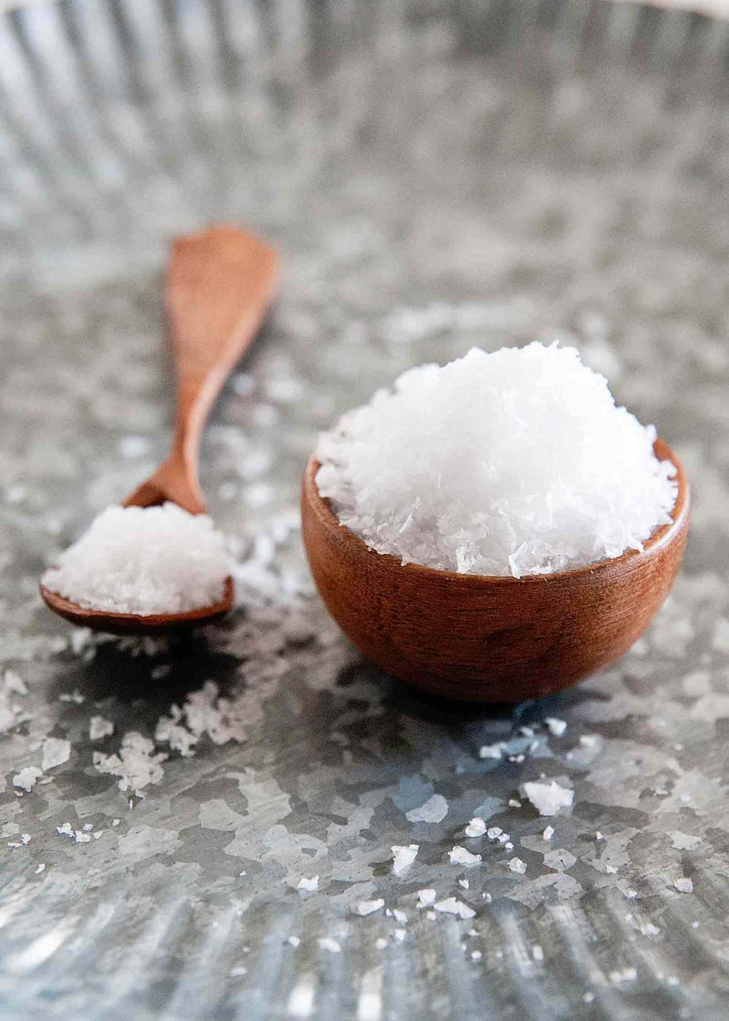 Flaky sea salt in bowl with small wooden spoon