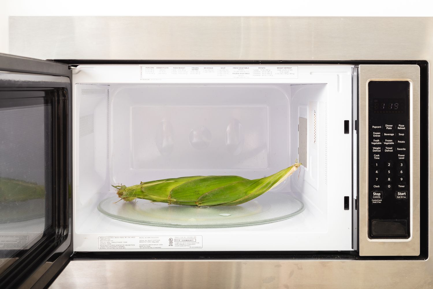 An ear of corn in a microwave to show how to cook corn on the cob.