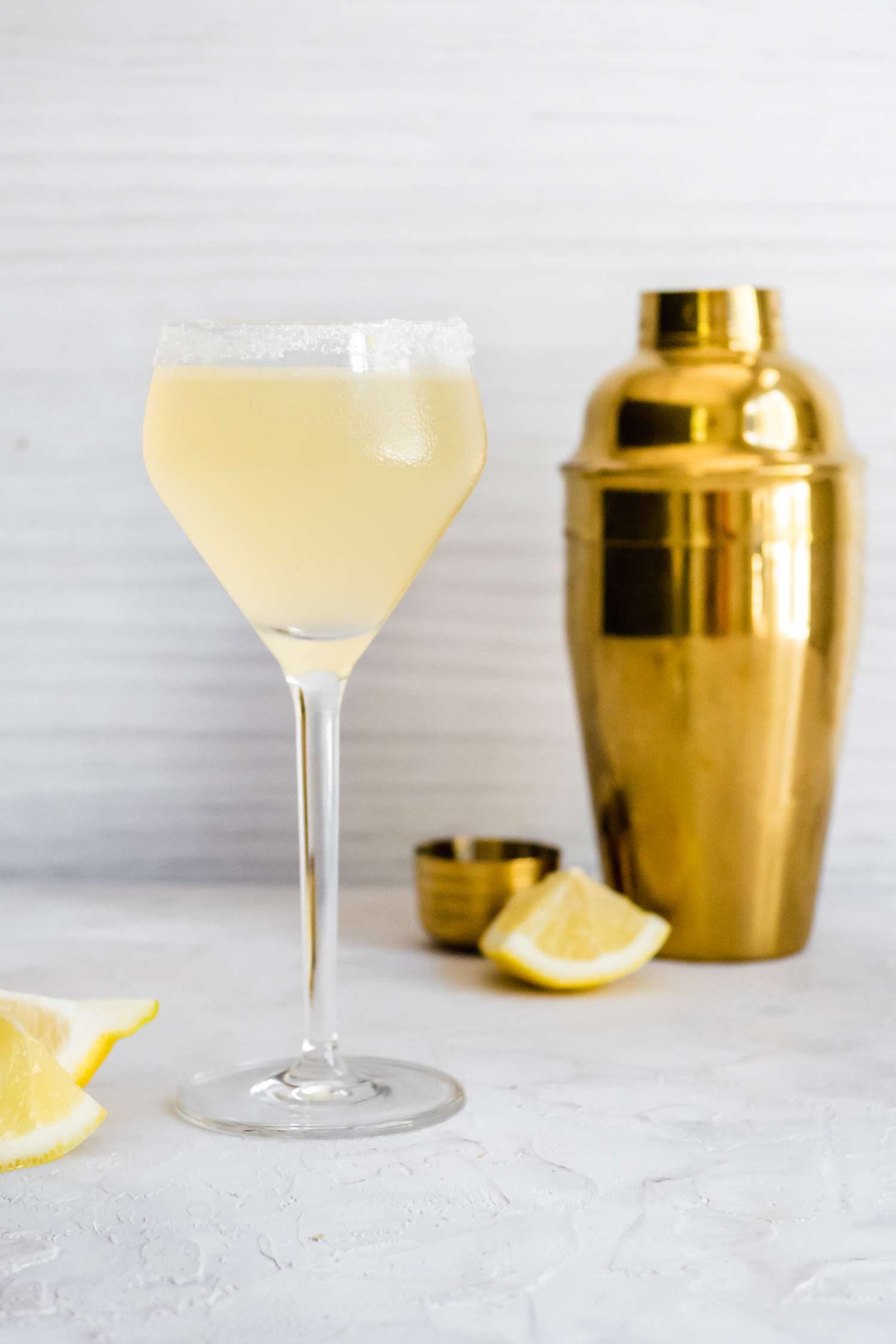 Lemon Drop Martini Surrounded by Lemon Wedges and a Shaker