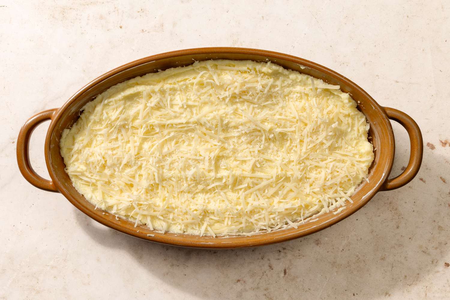 potato mixture in a baking dish, sprinkled with grated Parmesan cheese for Chantilly Potatoes