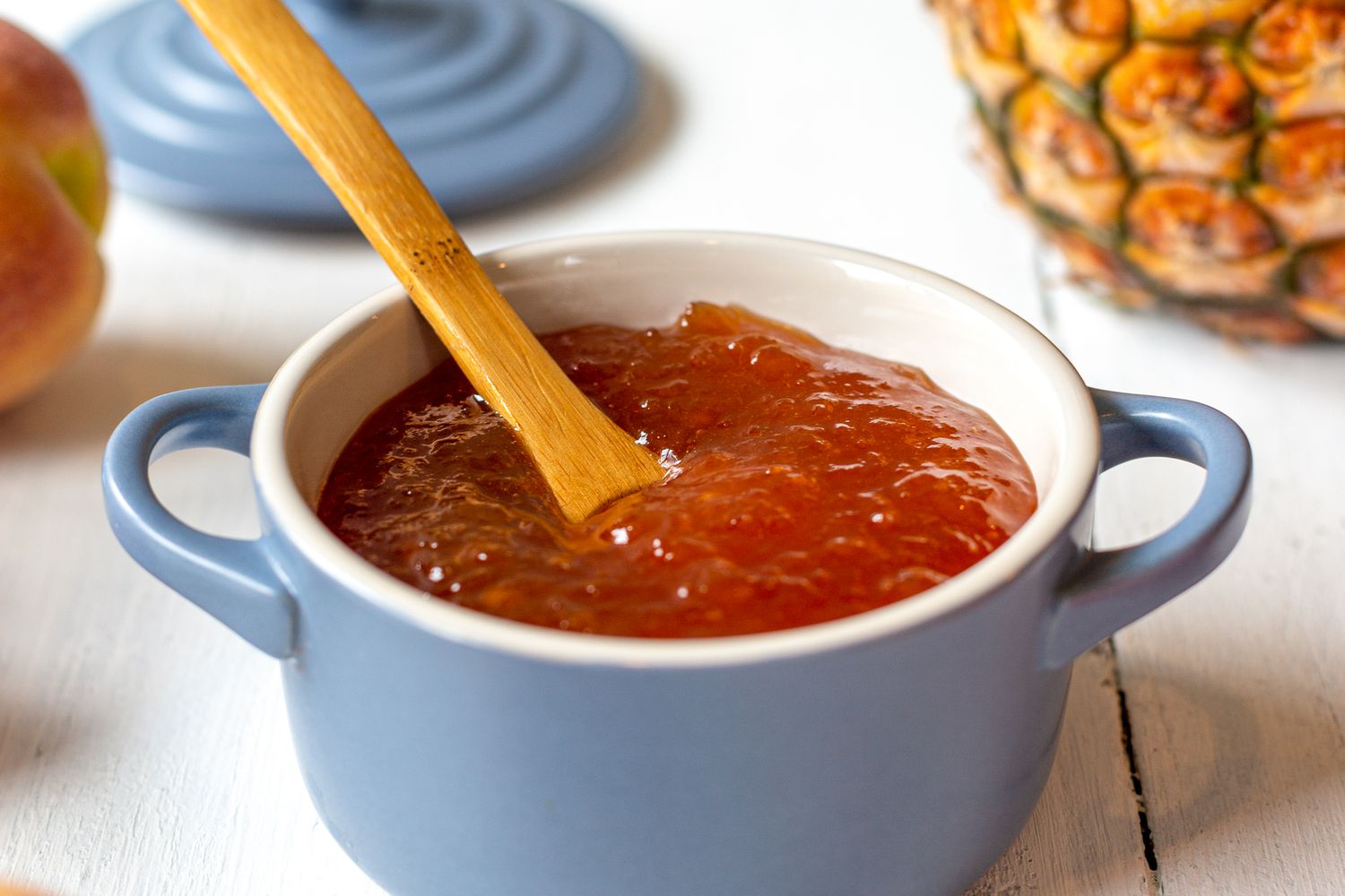 Peach and Pineapple Jam in a Small Dutch Oven Surrounded by Peaches and a Pineapple 