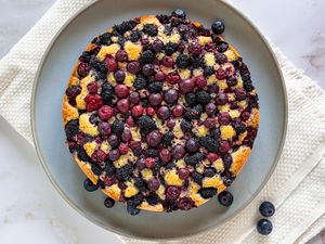 Blueberry Cake on a Plate With Rogue Blueberries on the Counter and Plate