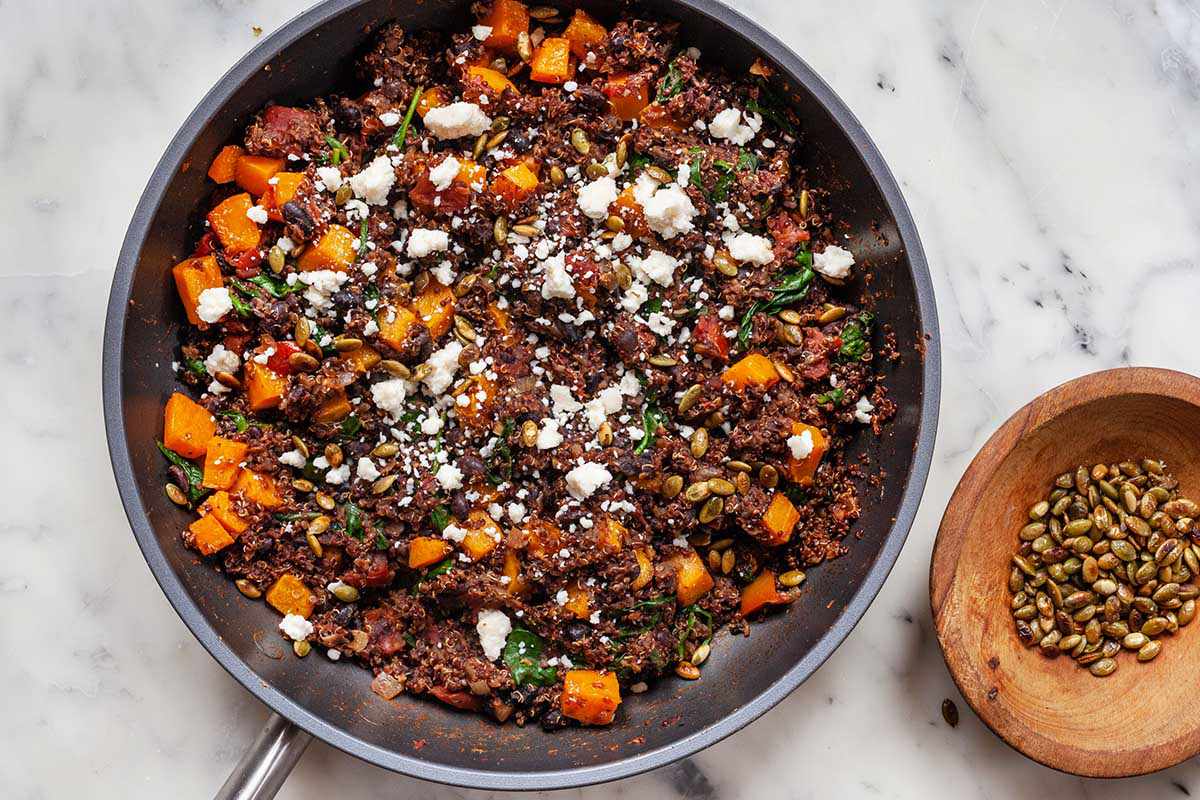 Vegetarian Skillet Dinner in a saute pan with a small bowl of pumpkin seeds to the right.