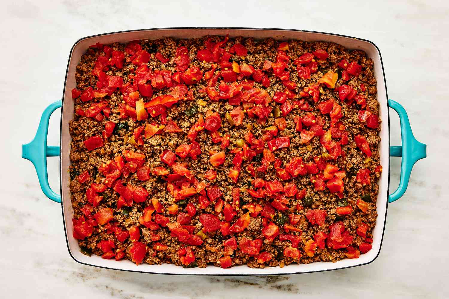 cooked ground beef and Rotel added to the casserole dish for Cattle Drive Casserole