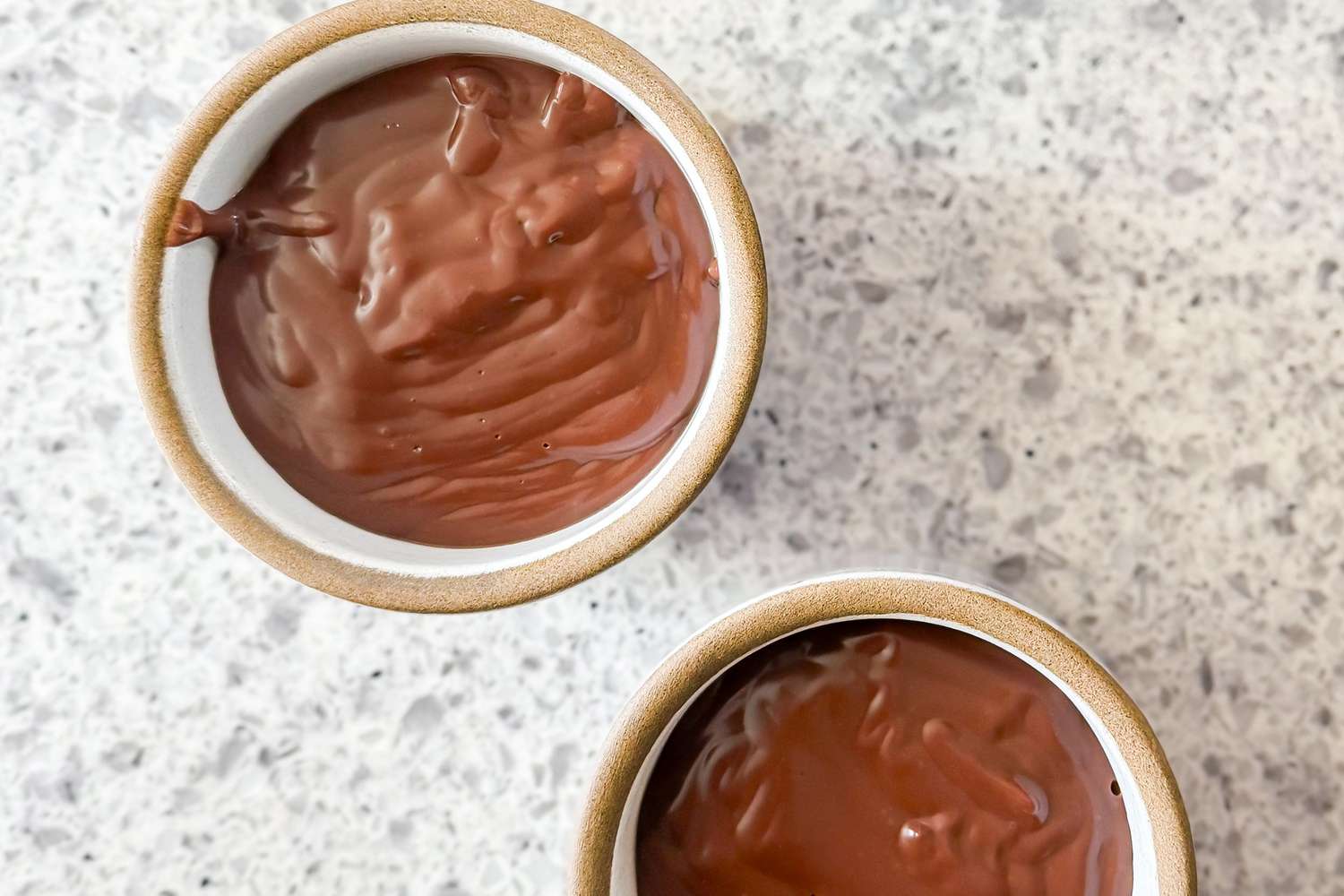 Two small ceramic bowls of rich-looking chocolate pudding