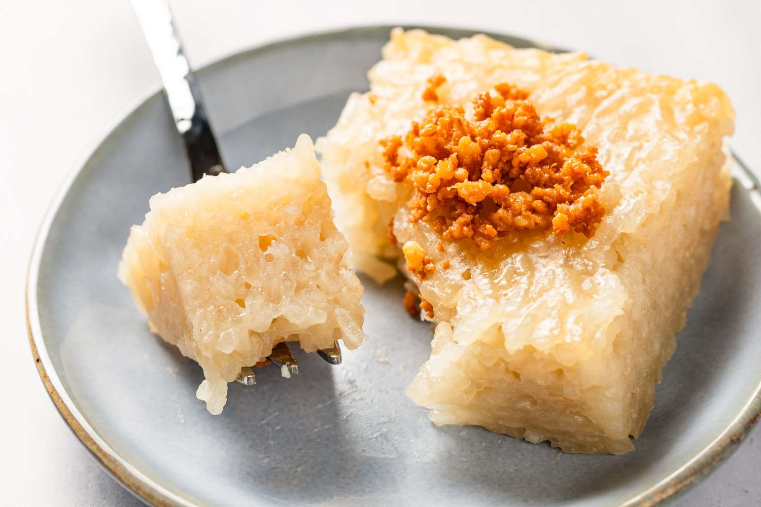 slice of biko (Filipino sticky rice cake) on a plate with a bit on a fork