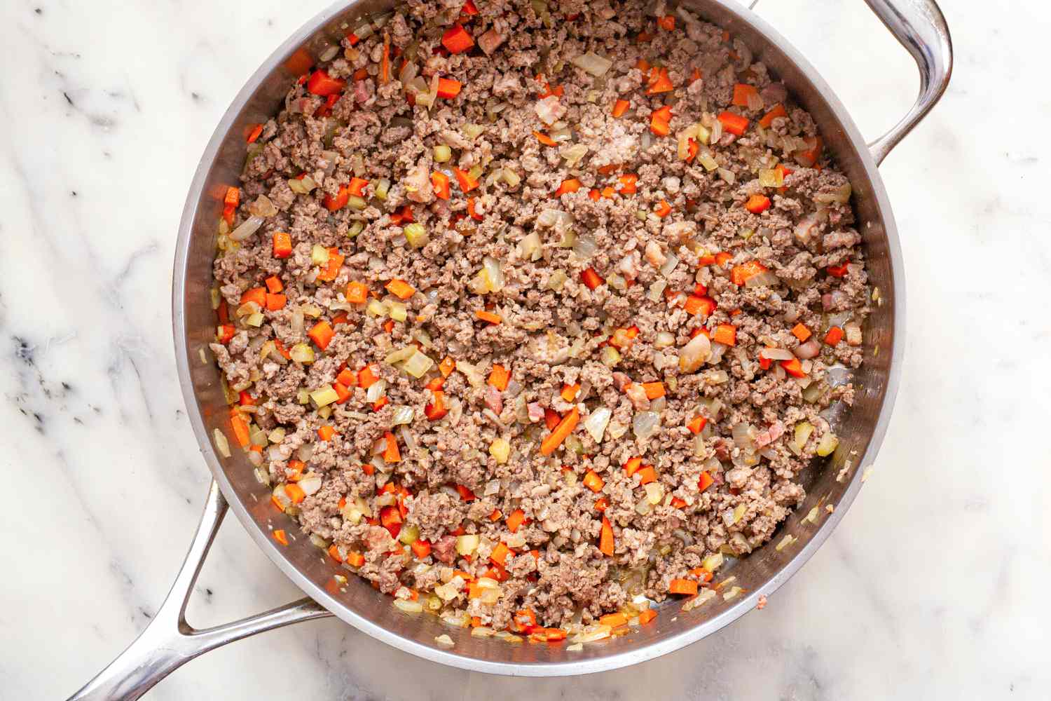 A skillet with ingredients to make bolognese sauce.