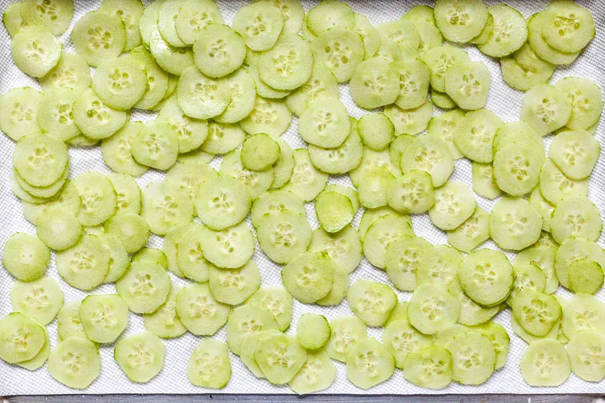Thinly sliced cucumbers set on paper towels for cucumber dill sandwiches.