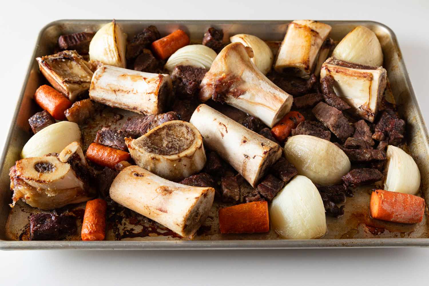 Roasting beef bones and vegetables to make a beef soup recipe.