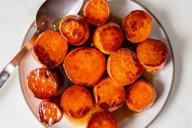 A plate of glazed sweet potato rounds served with a spoon