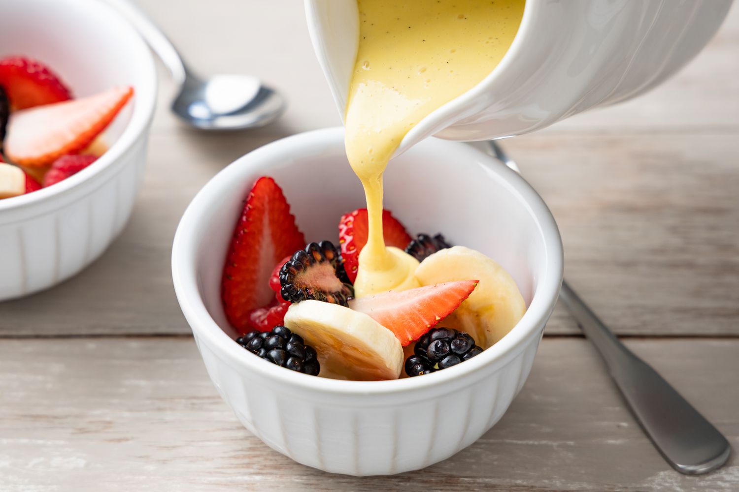 Creme Anglaise Poured over a Bowl of Fruit (Slices of Banana, Strawberries, and Blackberries)