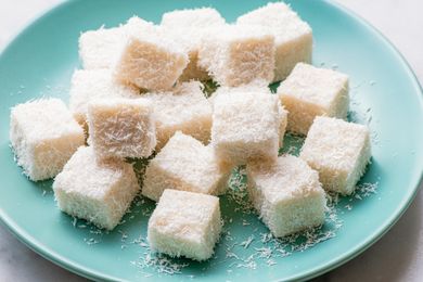 Small cubes of coconut milk pudding served on a plate, topped with shredded coconut