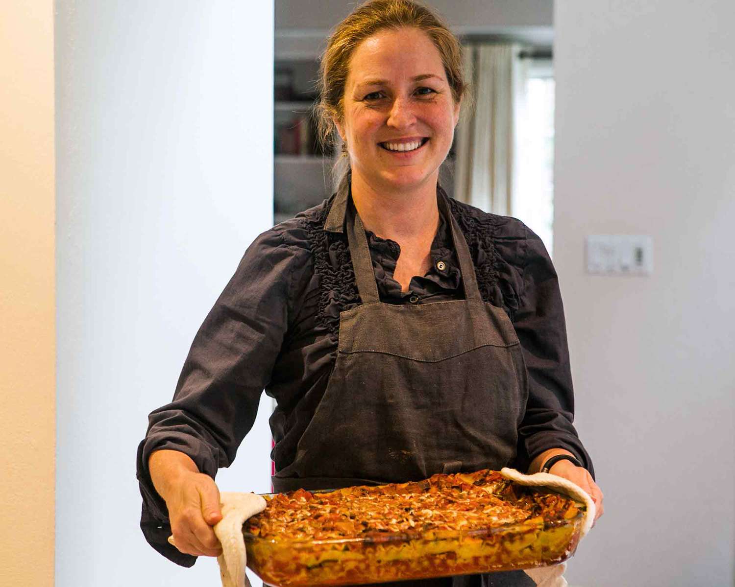 Elise Bauer holding a baking dish with Vegetarian Spinach Mushroom Lasagna